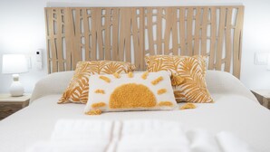 A neatly made bed with a white and yellow patterned pillow, a wooden headboard, and a bedside table with a lamp and a small white vase. - SANLUCAR DE BARRAMEDA CORNER (Unknown)