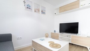A modern living room with a white sofa, a coffee table, a TV, and a minimalist cabinet. - SANLUCAR DE BARRAMEDA CORNER (Unknown)