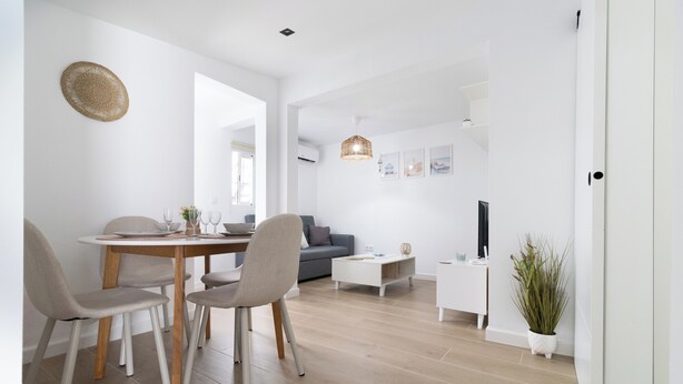 A modern living room with a dining area, a grey sofa, a TV, and a potted plant. - SANLUCAR DE BARRAMEDA CORNER (Unknown)