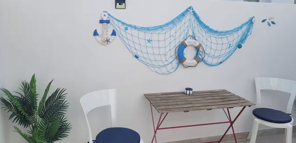 Une pièce avec un hamac, deux chaises, une petite table et une plante en pot.