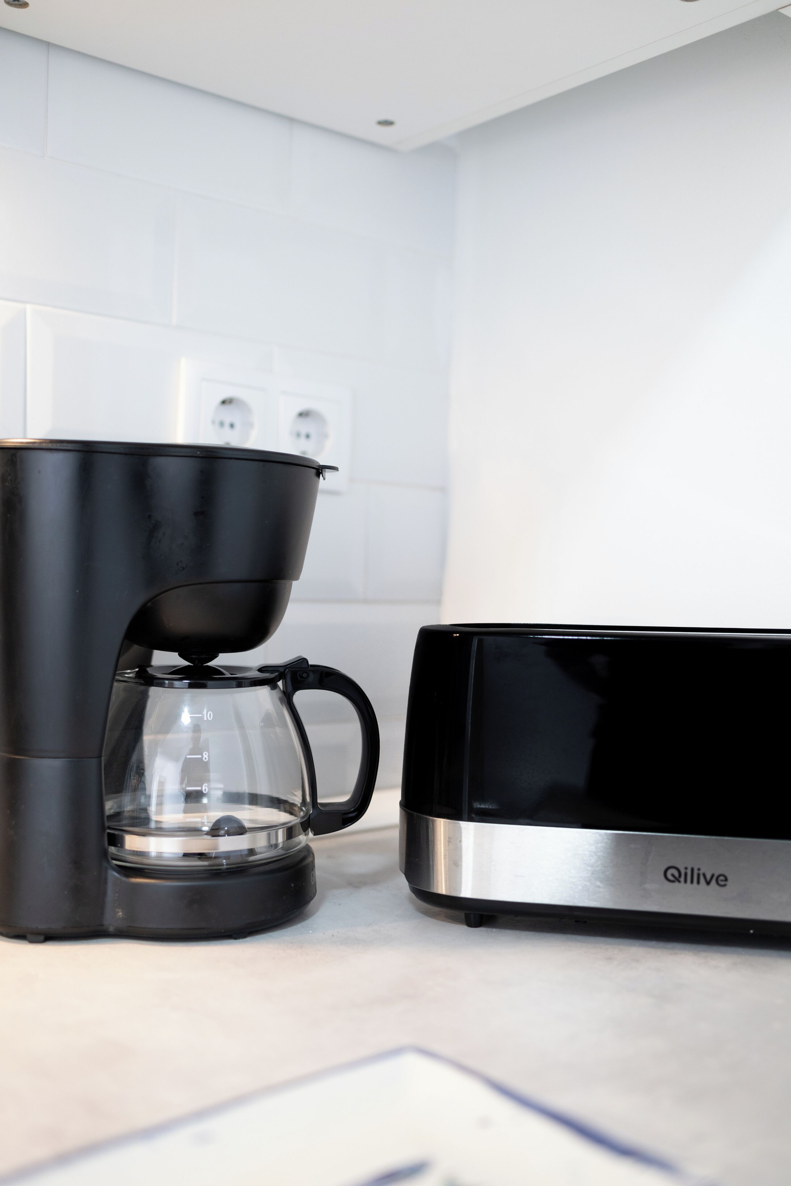 Een keuken met een zwarte koffiezetapparaat en een roestvrijstalen magnetron.