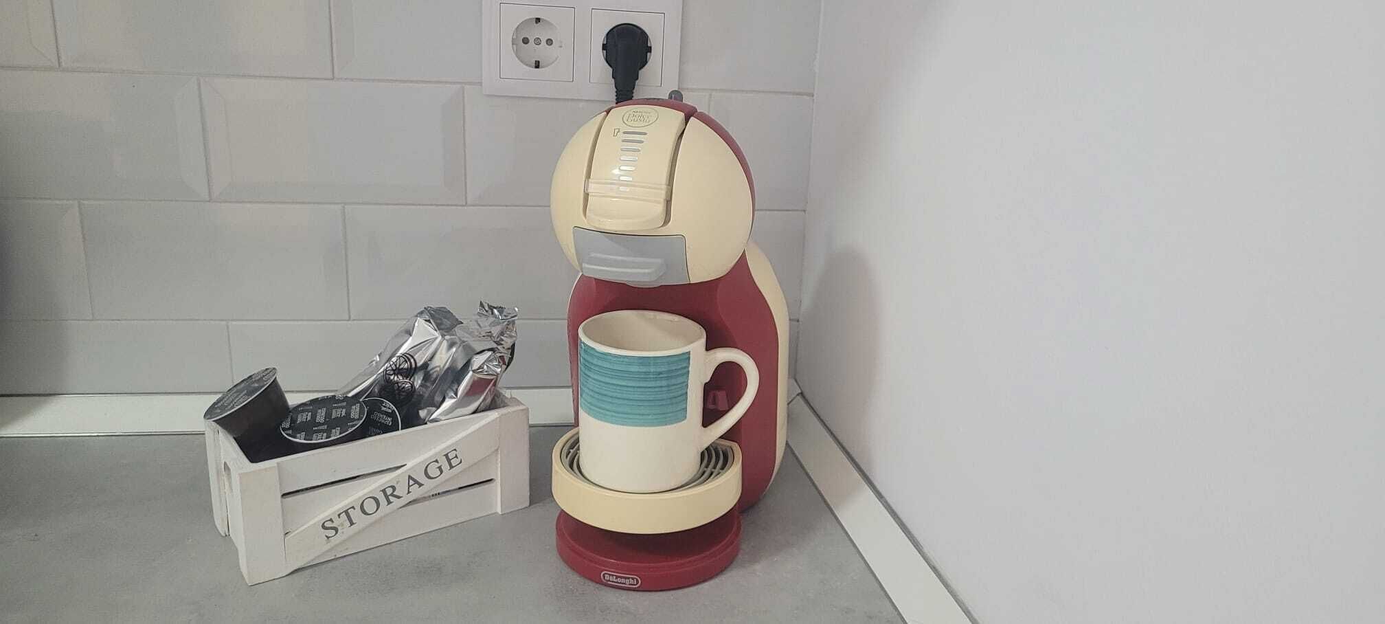 Eine Kaffeemaschine mit Tasse auf einer Arbeitsplatte, eine Aufbewahrungsbox mit dem Aufdruck 'STORAGE' und verschiedenen Gegenständen sowie eine Steckdose im Hintergrund.