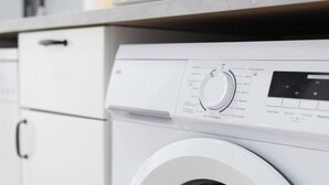 A front view of a modern laundry room with a front-loading washing machine, a dryer, and a countertop with various kitchen utensils. - SANLUCAR DE BARRAMEDA CORNER (Unknown)
