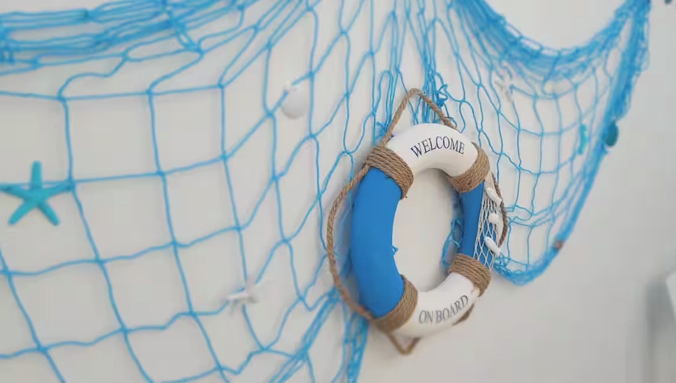 A blue lifebuoy with 'WELCOME' and 'ON BOARD' text, attached to a blue net.
