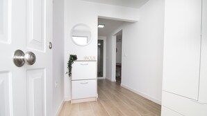 A hallway with white walls, a wooden floor, a white cabinet with drawers, and a round mirror on the wall. - SANLUCAR DE BARRAMEDA CORNER (Unknown)