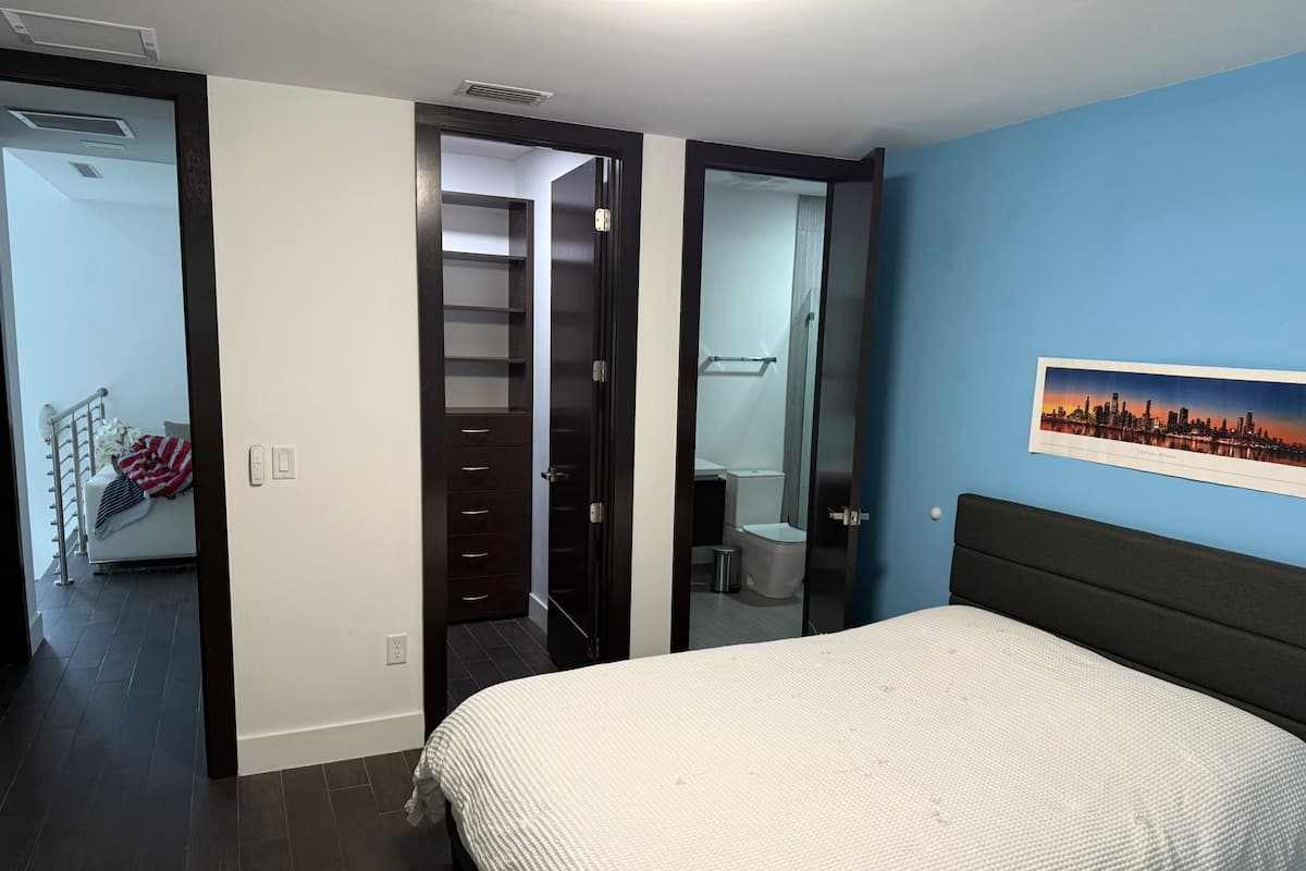 Een slaapkamer met een bed, een kledingkast, een badkamer en een trap.
