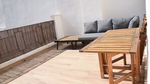 Un balcón con una mesa de madera y un sofá gris.