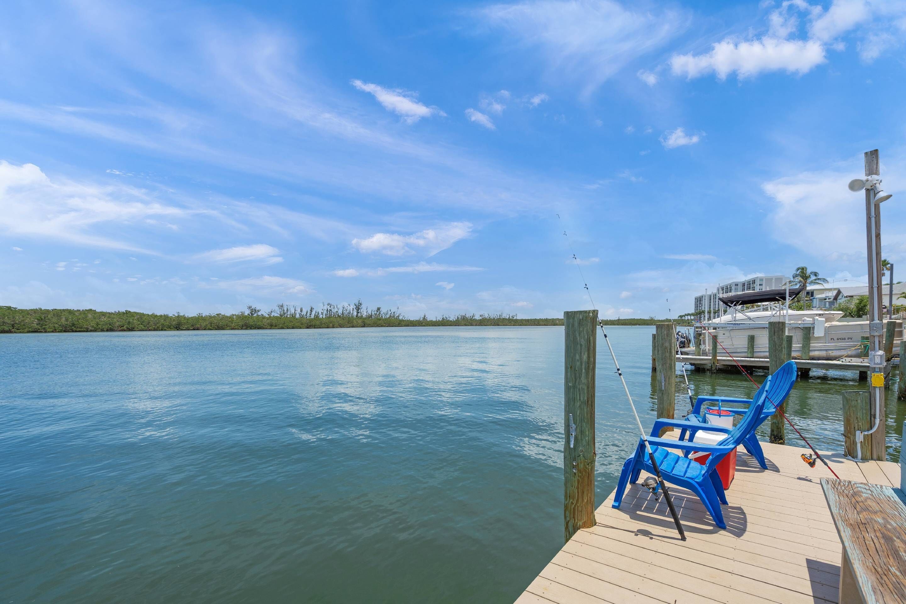 A dock with a wooden pier, a blue chair, and a fishing rod.