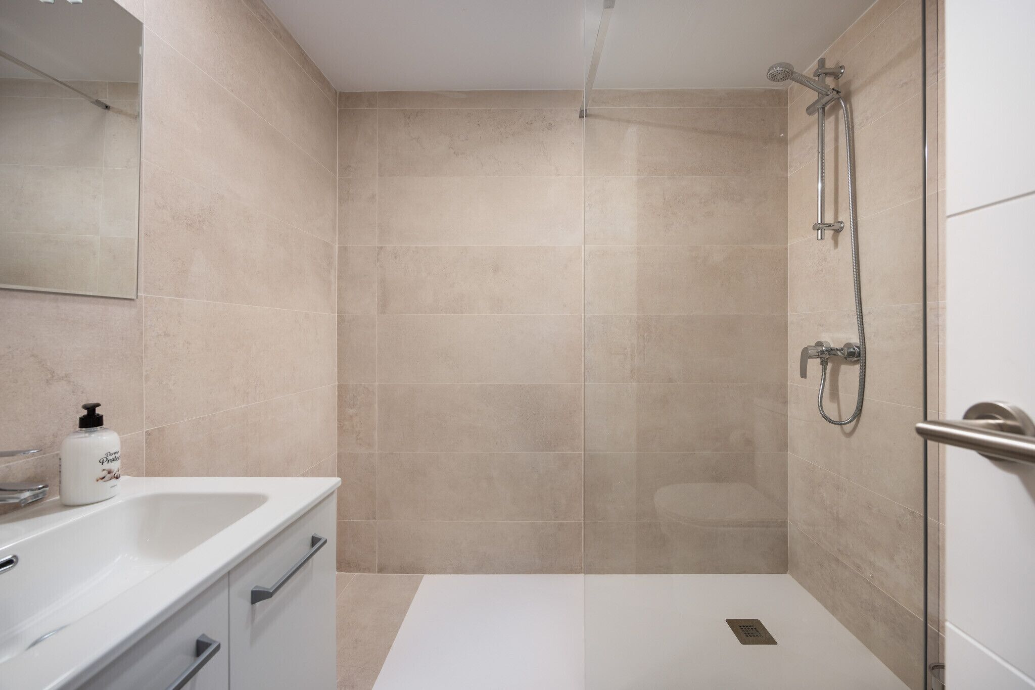 A modern bathroom with a shower, a sink, and a mirror.