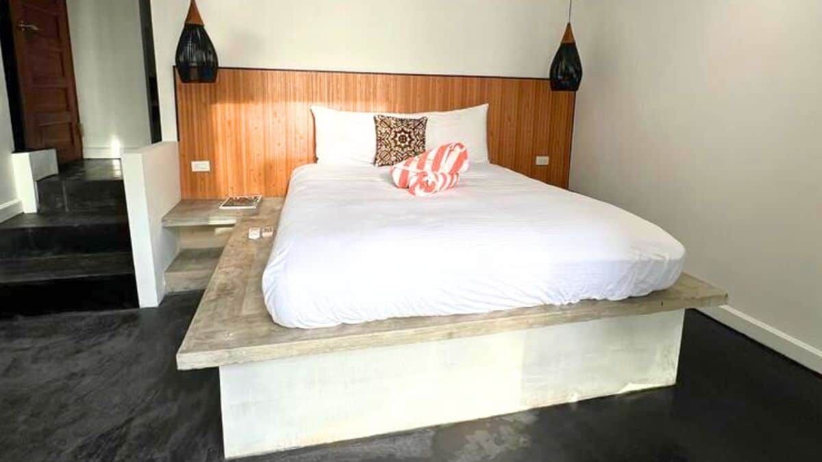 Een hotelkamer met een groot bed, een houten hoofdeinde en twee bedlampjes.