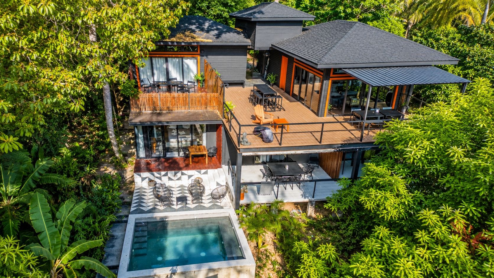 Ein modernes, zweistöckiges Haus mit Dachterrasse, Schwimmbad und üppiger Bepflanzung rund um das Anwesen.
