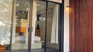 Une chambre moderne avec une porte vitrée donnant sur un balcon, un lit avec des oreillers et un mur en bois.