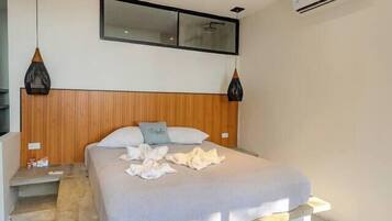 Een moderne slaapkamer met een bed, nachtkastjes, een houten hoofdbord, een airconditioner en hanglampen.