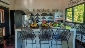 Een keuken met een centraal eiland, barkrukken en een verscheidenheid aan fruit en groenten.