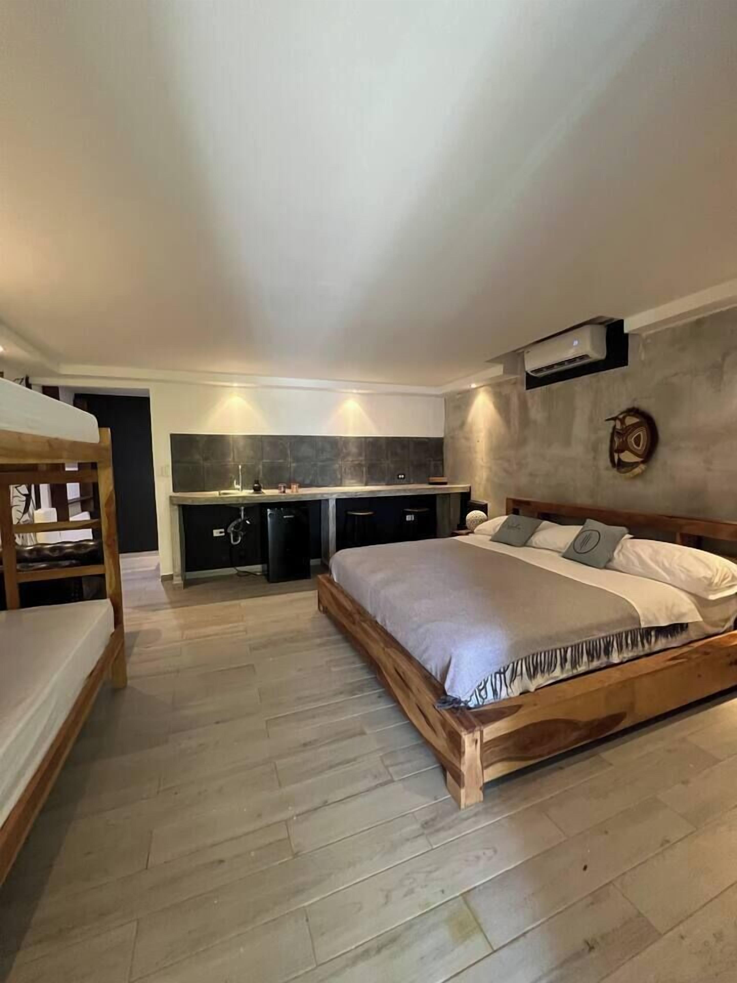 Een slaapkamer met een houten bed, een klein bureau en een kitchenette.
