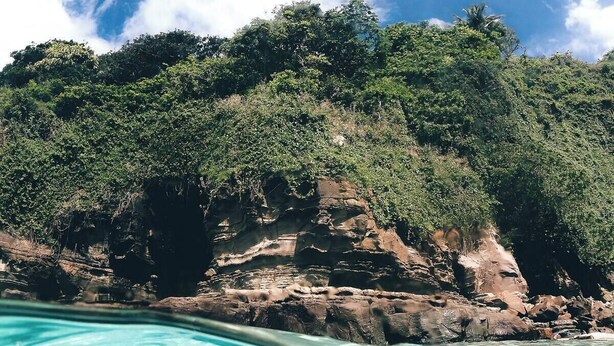 Un paysage côtier caractérisé par une eau turquoise et limpide, des falaises rocheuses et une végétation luxuriante.