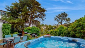 A hot tub in a garden with a table and chairs, surrounded by lush greenery and trees. - La Jolla Historic Gem | Hot Tub, Game Room, Garden Oasis w/ Firepit & Courtyard Dining (La Jolla)