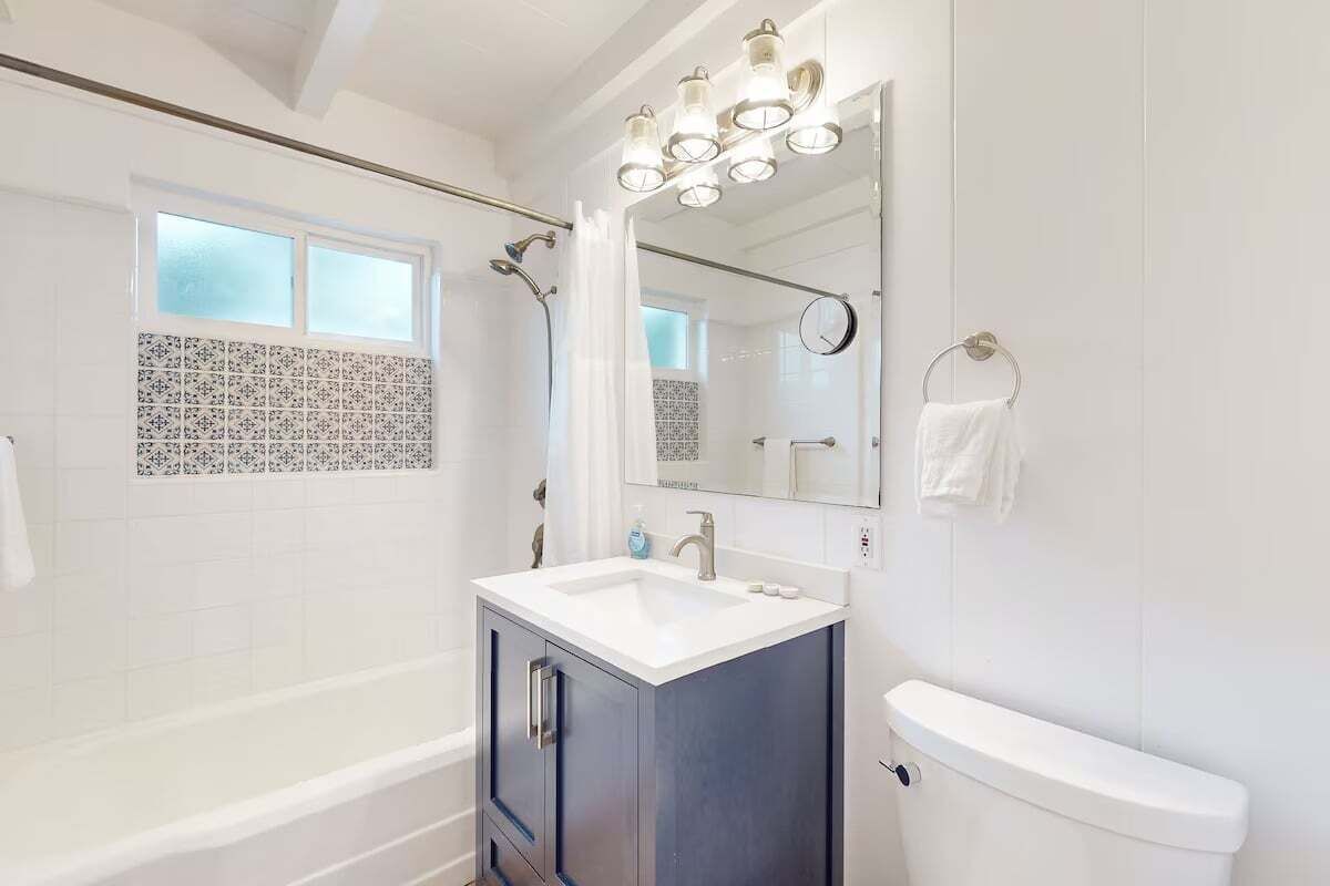 A modern bathroom with a bathtub, a vanity with a sink, a toilet, and a shower area.