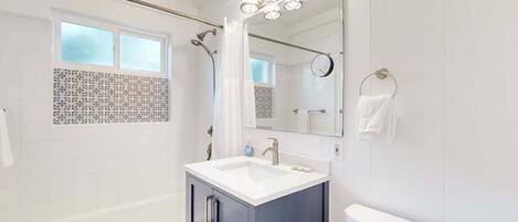 A modern bathroom with a bathtub, a vanity with a sink, a toilet, and a shower area.