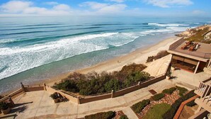 Ein Strandgrundstück mit einer Terrasse mit Meerblick, einem Pool und einem angelegten Garten.