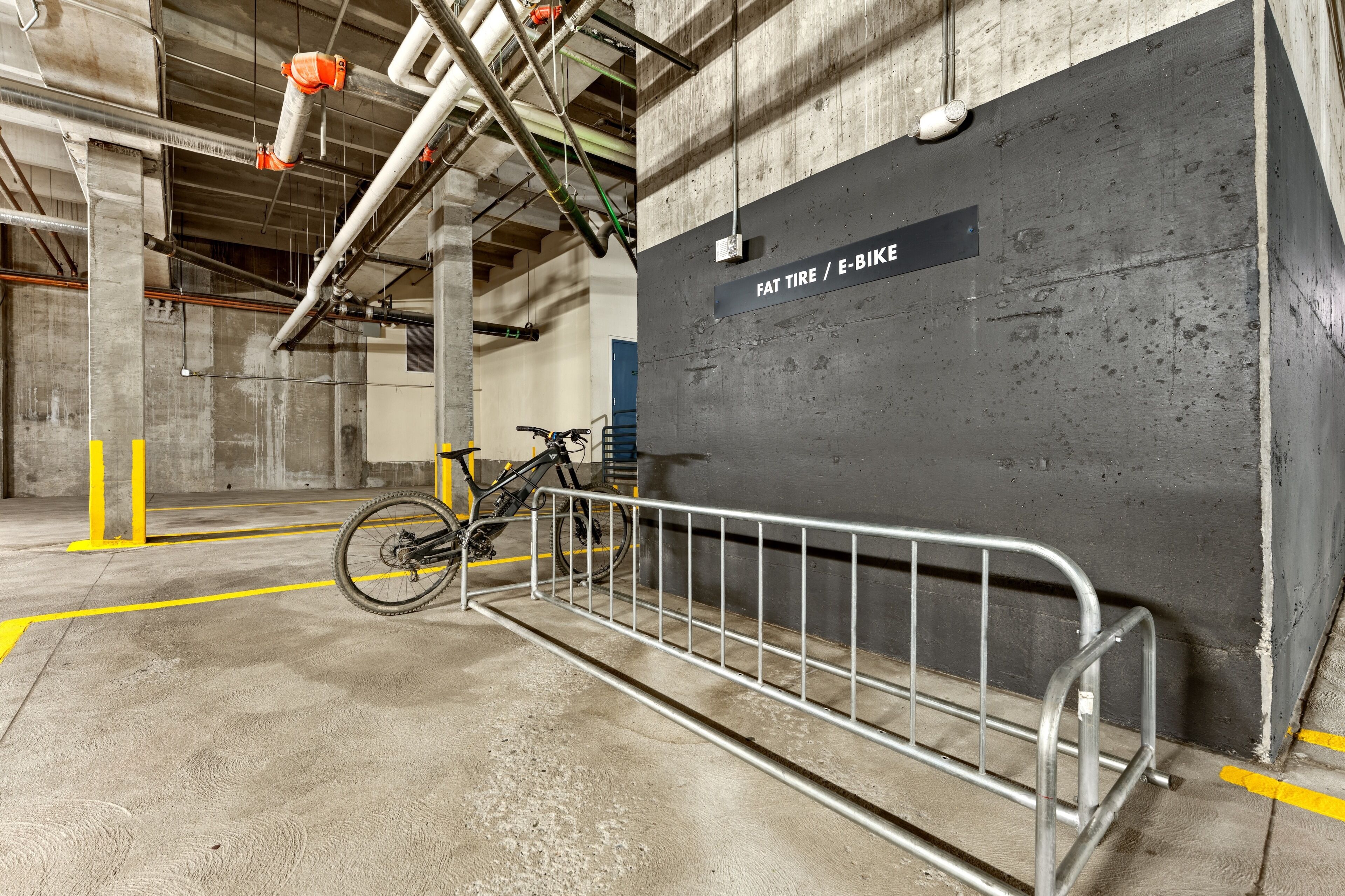 A bicycle parked in a concrete parking area with a sign indicating a space for fat tire and e-bike parking.