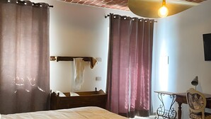 A bedroom with a brick ceiling, a bed with a white and yellow bedspread, a wooden nightstand, a desk with a chair, and a hanging light fixture. - Room 'Cùcu' with Shared Garden, Wi-Fi and Air Conditioning (Quargnento)