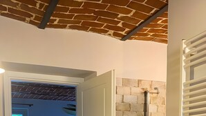 A room with a bed, a white sink, a shower, and a white door. - Room 'Cùcu' with Shared Garden, Wi-Fi and Air Conditioning (Quargnento)