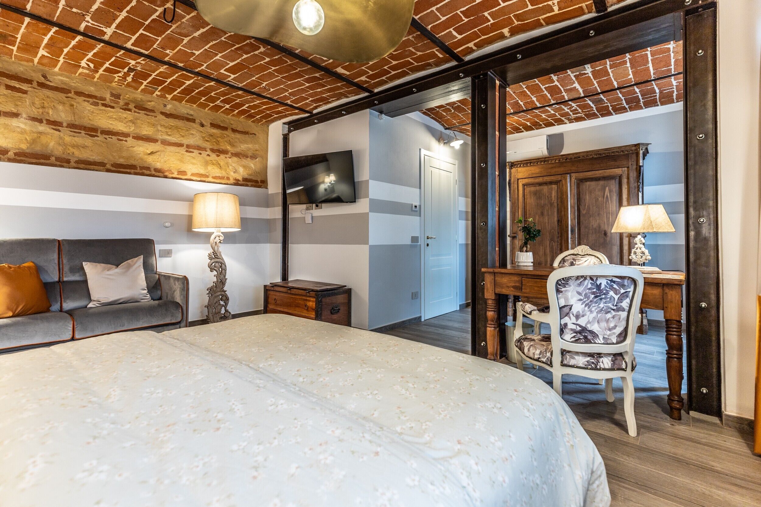 Een slaapkamer met een groot bed, een bureau, een stoel, een televisietoestel en een kledingkast.