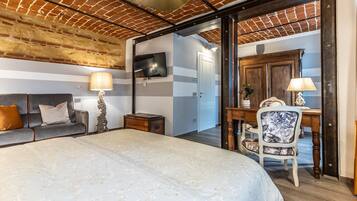 Een slaapkamer met een groot bed, een bureau, een stoel, een televisietoestel en een kledingkast.