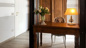 Een kamer met een houten bureau, een vaas met bloemen, een lamp en een plafond van baksteen.