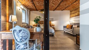 Een kamer met een bakstenen plafond, een bed, een bank, een eettafel met stoelen en een lamp.