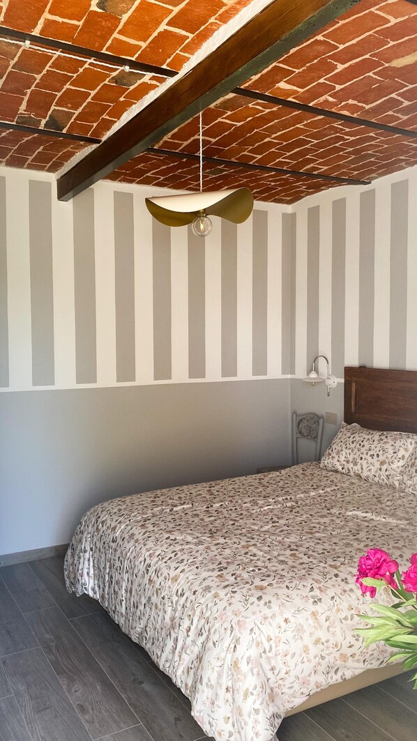Un dormitorio con cama, ventilador de techo, lámpara de pared y techo con diseño de ladrillos.