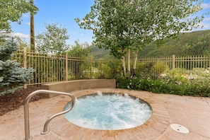 A hot tub surrounded by a wooden fence, with a mountainous landscape in the background.