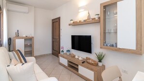 A living room with a TV, wooden shelves, a sofa, and a door.