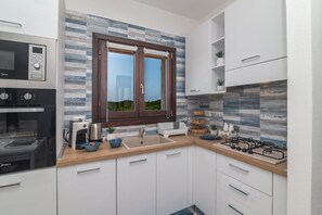 A modern kitchen with a built-in oven, a coffee maker, and a window with a view of greenery.