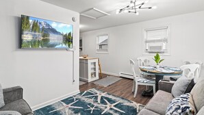A modern living room with a flat-screen TV, a dining area with a table and chairs, and a cozy seating area with a patterned rug. - Cozy 2 Bedroom with a view with WiFi, AC (Seaside Heights)