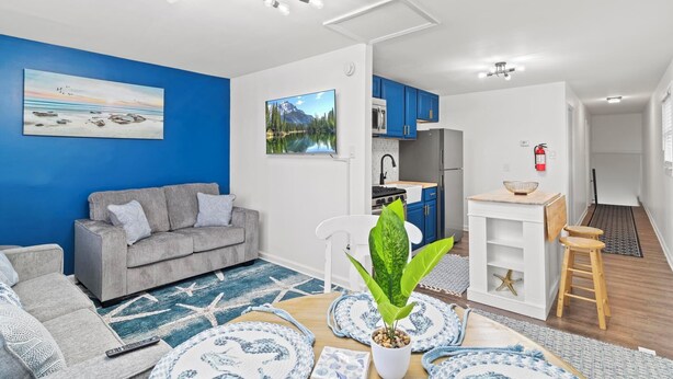 A modern living room with a grey sofa, a blue accent wall, and a large window. - Cozy 2 Bedroom with a view with WiFi, AC (Seaside Heights)