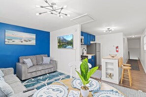 Ein modernes Wohnzimmer mit grauem Sofa, blauer Akzentwand und einem großen Fenster.