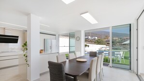 A modern kitchen with white cabinets, a black range hood, and a dining area with a table and chairs. - Private Villa with Heated Pool, Air Conditioning, and Football Field (Candelaria)