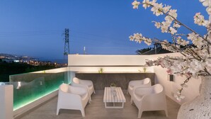 A rooftop terrace with a glass infinity pool, white chairs, a small table, and a potted plant. - Private Villa with Heated Pool, Air Conditioning, and Football Field (Candelaria)