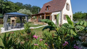 Una casa amb un porxo cobert, un jardí ple de plantes tropicals i façana blanca.