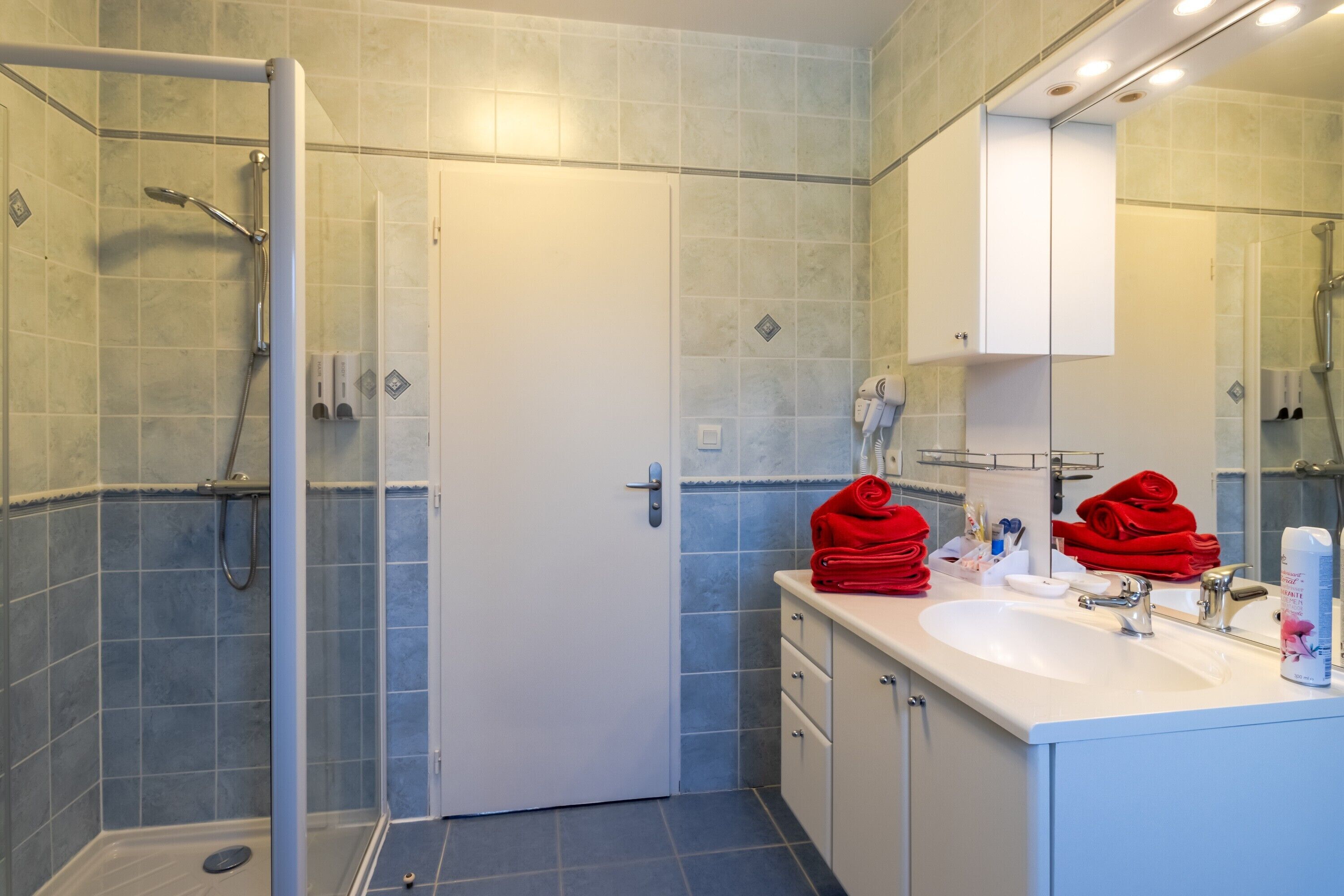Un baño con ducha, lavabo y espejo.