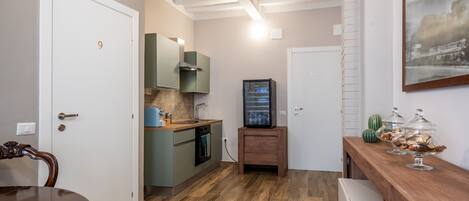 A compact kitchen with a dining table, a built-in oven, and a television.