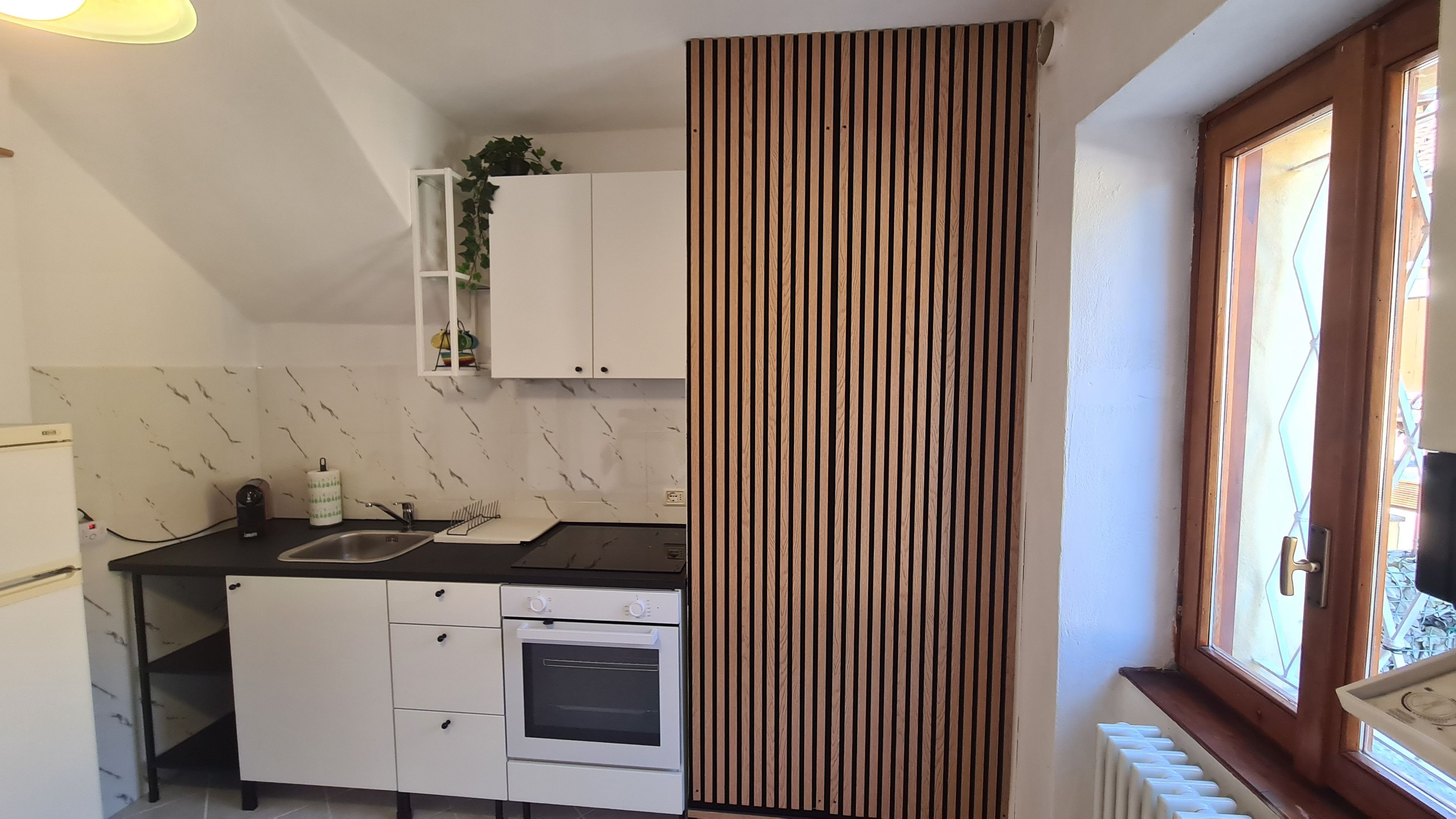 A compact kitchen with a built-in oven, a sink, and a window with a view.