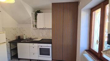A compact kitchen with a built-in oven, a sink, and a window with a view.