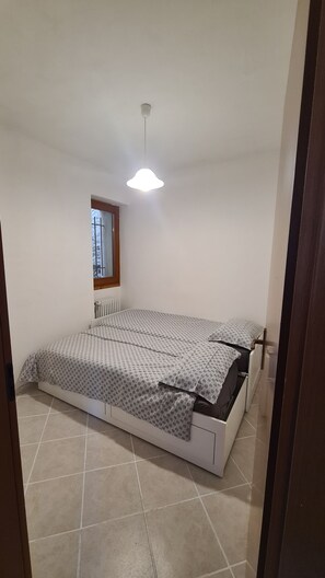 Une chambre à coucher avec un lit, une fenêtre et un luminaire au plafond.
