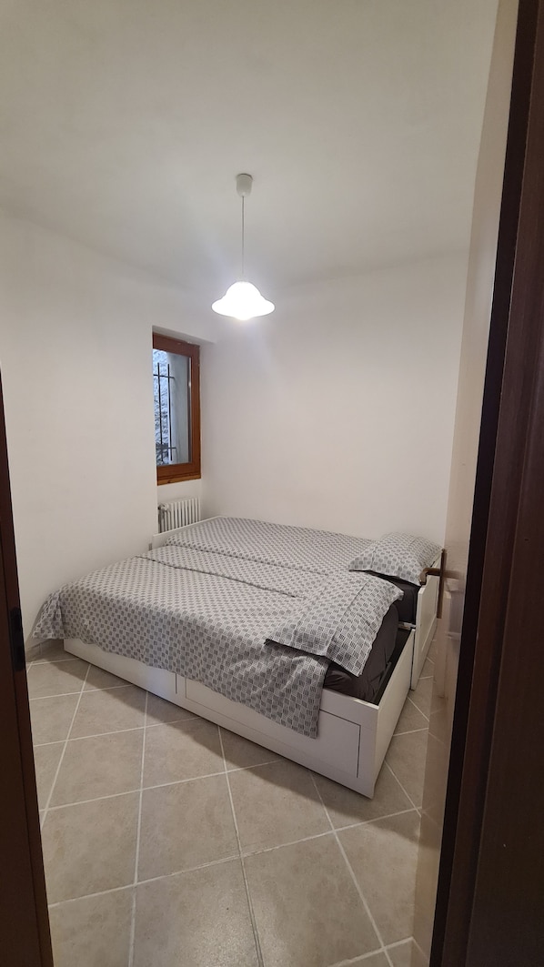 A bedroom with a bed, a window, and a ceiling light.