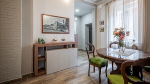 Un comedor con una mesa de madera, sillas, un jarrón con flores, un cuadro en la pared y una pared de ladrillo.