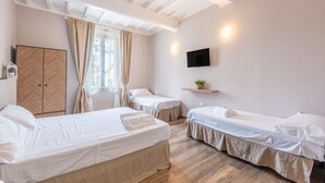 Habitación de hotel con dos camas, un televisor, un armario de madera y una ventana con cortinas.