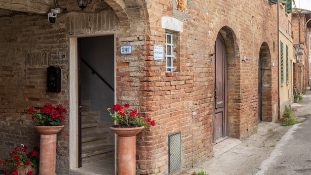 A brick building with a door, a window, and a sign with the number 241.